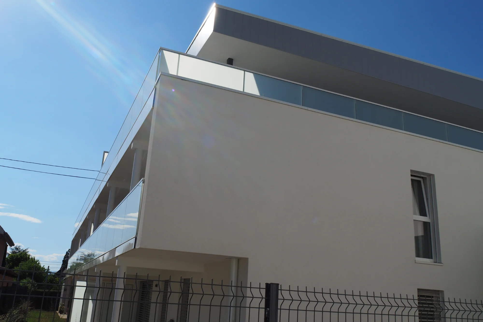 Angle du bâtiment avec ses balcons filants et son attique en zinc